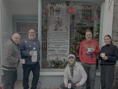 FASD Ireland team outside their pop-up Christmas window with holiday messaging banner